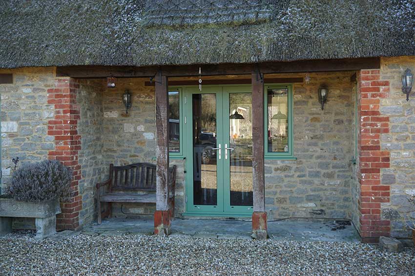 Green French doors thatched cottage